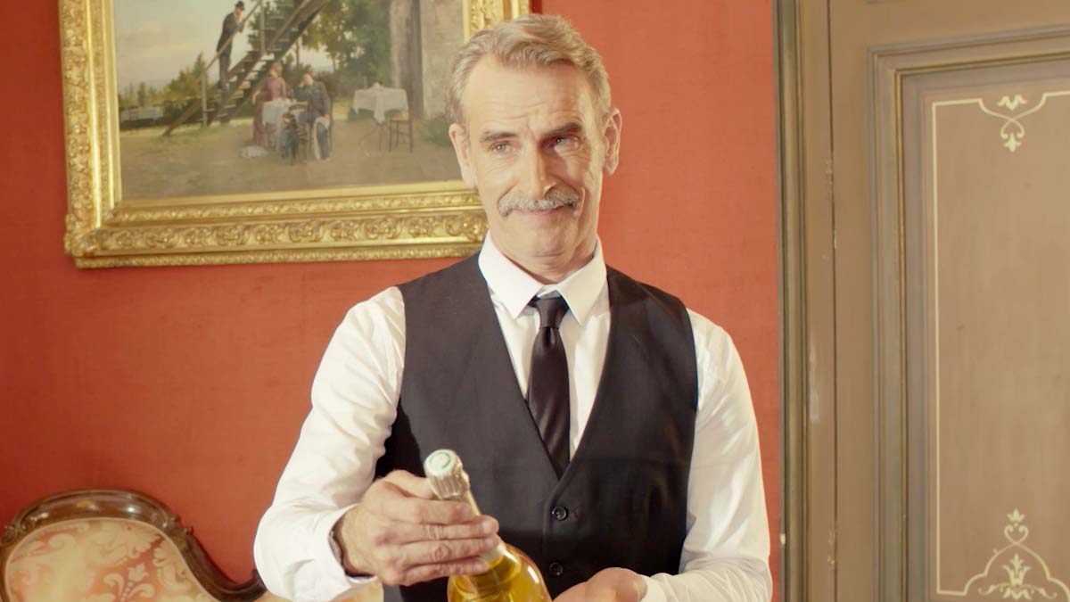 Un sommelier présentant une bouteille de Champagne Deutz dans un salon élégant