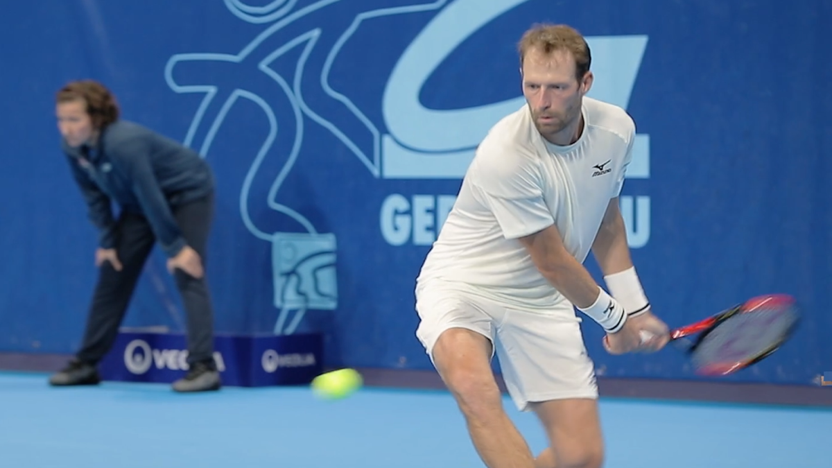Joueur de tennis en plein revers sur court bleu lors de l'Open d'Orléans