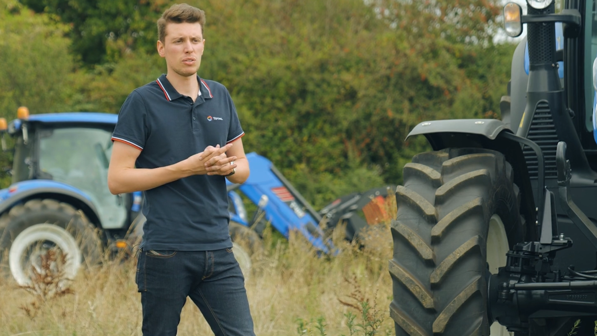 Un homme en polo TotalEnergies s'exprimant devant des tracteurs agricoles