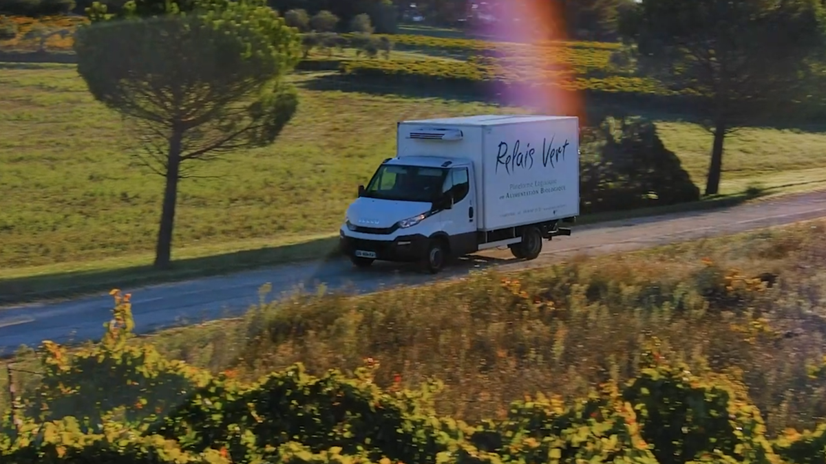 Camion frigorifique Relais Vert circulant sur une route de campagne entre les vignes