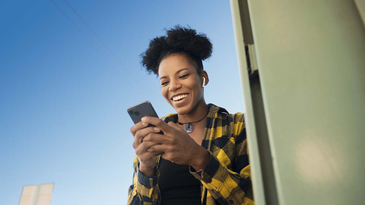 Une jeune femme souriante consultant son smartphone, illustration de l'application SFR et Moi