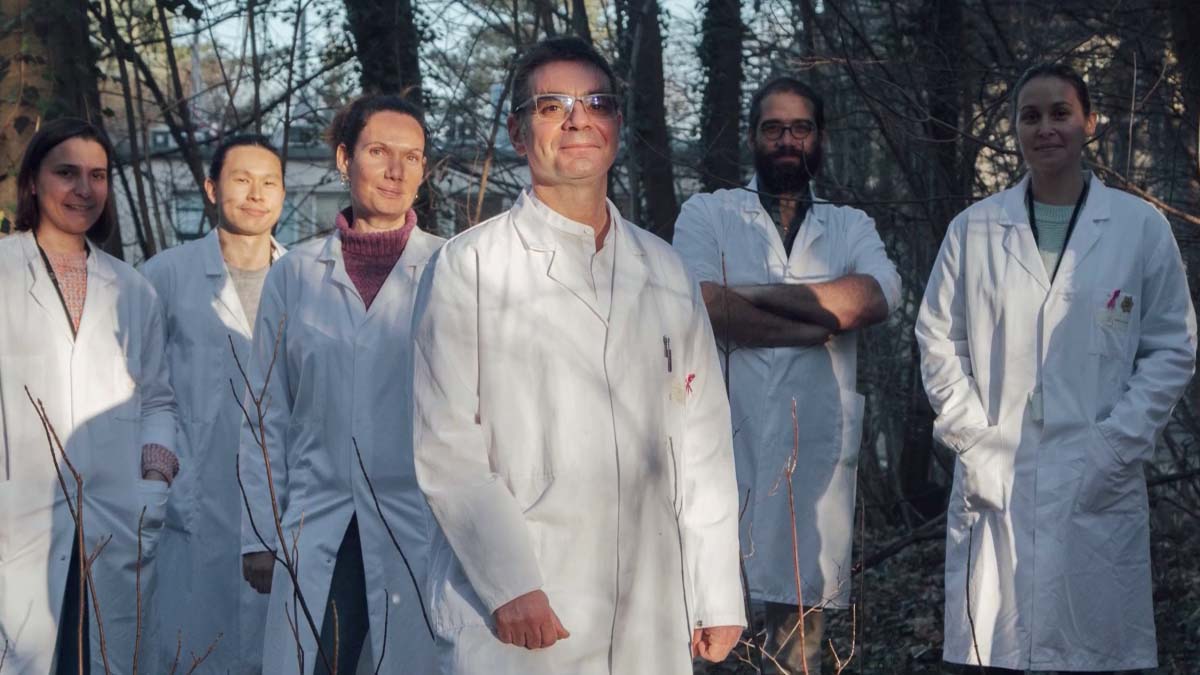 Groupe de six personnes en blouse blanche posant en forêt