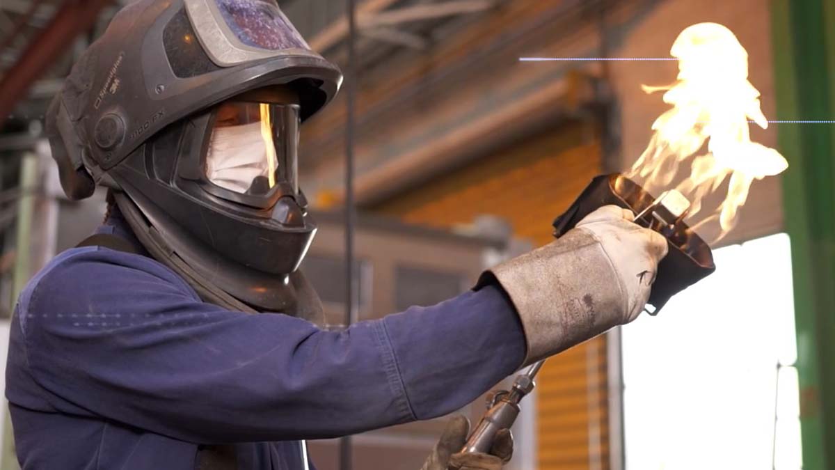 Ouvrier avec masque de protection maniant un chalumeau, atelier industriel