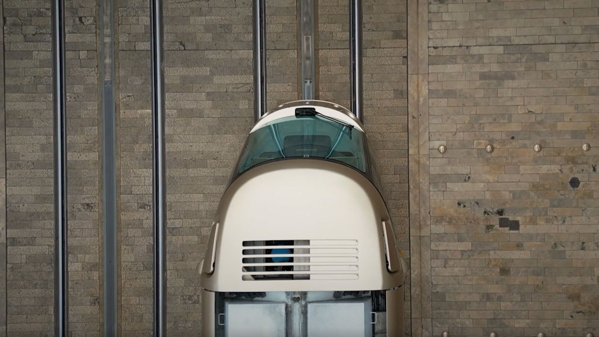 Vue de face d'un véhicule futuriste au design rétro-spatial, devant un mur en pierre