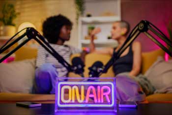 Enseigne lumineuse "On Air" devant deux invités en pleine discussion